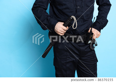 Cropped image of male policeman officer wearing black uniform with professional ammunition isolated on blue background. Cropped image of male policeman officer wearing black uniform with professional ammunition isolated on blue background. 86370155