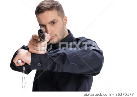 Half-length portrait of young man, policeman officer wearing black uniform standing with gun isolated on white background. Concept of job, caree, law and order. Half-length portrait of young man, policeman officer wearing black uniform standing with gun isolated on white background. Concept of job, caree, law and order. 86370177