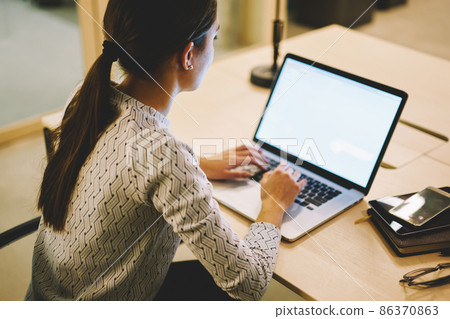 Unrecognizable female looking at screen and typing 86370863