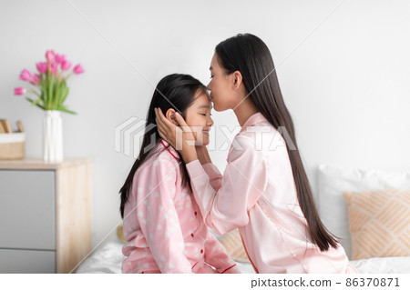 Cheerful japanese millennial female kissing at forehead of teenage girl in bedroom interior, profile, free space 86370871