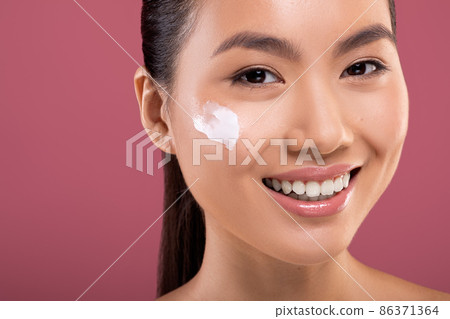 Smiling asian woman with moisturizer cream on her cheeks 86371364