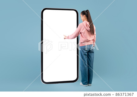 Woman with long hair standing in front of huge smartphone 86371367