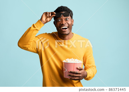 Amazed black man holding basket with popcorn, holding 3d glasses Amazed black man holding basket with popcorn, holding 3d glasses 86371445