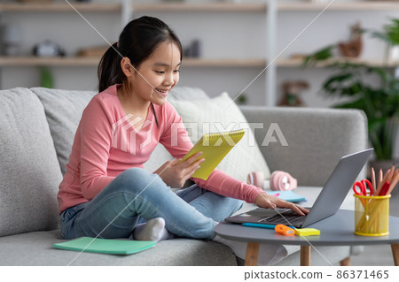 Happy asian girl doing homework, using laptop 86371465