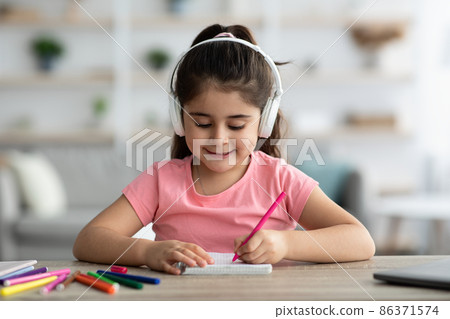 Kids Leisure. Little Arab Girl Wearing Wireless Headphones Drawing At Home Kids Leisure. Little Arab Girl Wearing Wireless Headphones Drawing At Home 86371574