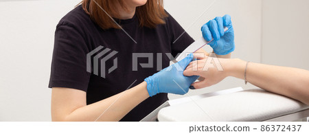 The master in the beauty salon makes the girl a manicure. The master in the beauty salon makes the girl a manicure. 86372437
