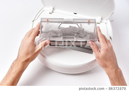 Take out the transparent dust container from the robot vacuum cleaner after cleaning the house. The container is completely clogged with dust Take out the transparent dust container from the robot vacuum cleaner after cleaning the house. The container is completely clogged with dust 86372870