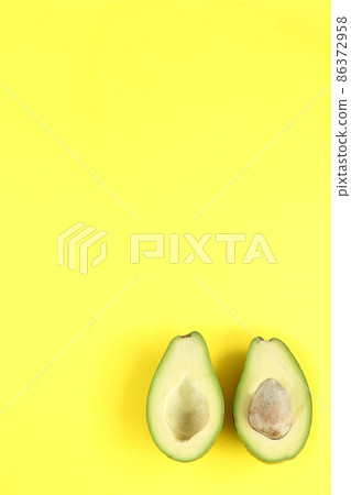 Two halfs of avocado with and without seed on yellow background. Two halfs of avocado with and without seed on yellow background. 86372958