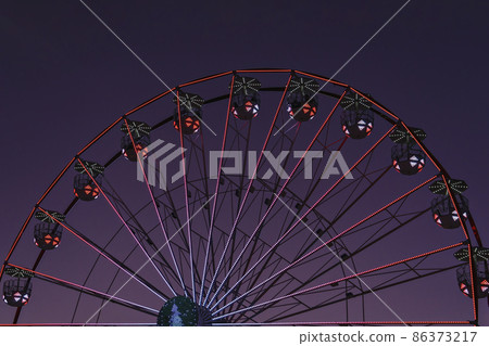 Closeup colorful Ferris wheel against sunset very peri sky. Abstract futuristic urban architecture, motion blur, selective focus Closeup colorful Ferris wheel against sunset very peri sky. Abstract futuristic urban architecture, motion blur, selective focus 86373217