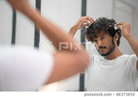 Male rubbing the hairstyling product into his curls 86373650