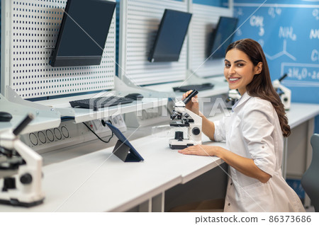 Woman sitting near microscope looking at camera 86373686
