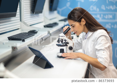 Woman sideways to camera looking through microscope 86373693