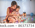 Little sisters having fun at home with chrismass lights. 86373734