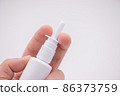 Holding nasal spray between fingers isolated on white background 86373759