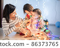 Mother with her daughters play with christmass lights 86373765