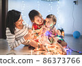 Mother with her daughters play with christmass lights 86373766