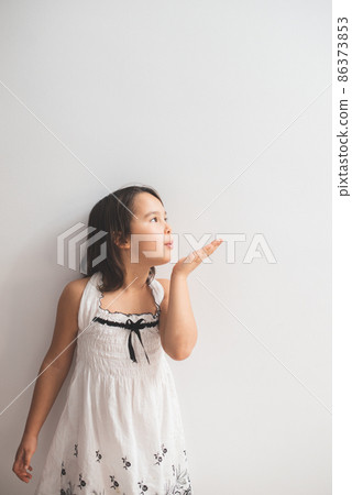 Cute girl standing next to an white wall and blowing kisses Cute girl standing next to an white wall and blowing kisses 86373853
