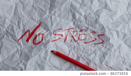 The concept of stress reduction. The word stress is written in red pencil on white crumpled paper. The concept of stress reduction. The word stress is written in red pencil on white crumpled paper. 86373858