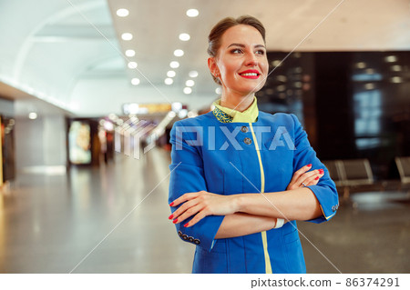 Cheerful female flight attendant standing at airport 86374291