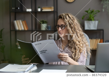 Young serious businesswoman looking through financial documents Young serious businesswoman looking through financial documents 86374320