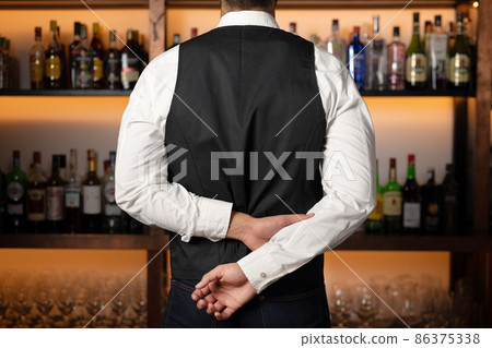 Backside of elegant bartender selecting beverage for customers in restaurant. Backside of elegant bartender selecting beverage for customers in restaurant. 86375338