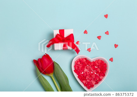 Craft gift box with a red ribbon, flowers and a paper hearts on a blue background for Valentine's Day. Mother's Day. Craft gift box with a red ribbon, flowers and a paper hearts on a blue background for Valentine's Day. Mother's Day. 86375372