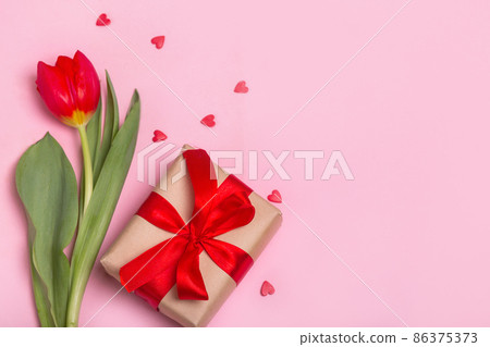 Craft gift box with a red ribbon, flowers and a paper hearts on a pink background for Valentine's Day. Mother's Day. Craft gift box with a red ribbon, flowers and a paper hearts on a pink background for Valentine's Day. Mother's Day. 86375373