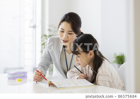 Girl elementary school student receiving individual guidance at a cram school Girl elementary school student receiving individual guidance at a cram school 86375684
