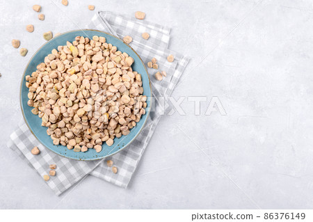 Dry Cicerchia or indian pea on a ceramic plate with napkin on grey table background, gluten free food, copy space 86376149