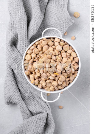 Cicerchia or indian pea in a white bowl with napkin on grey table background, gluten free food. Cicerchia or indian pea in a white bowl with napkin on grey table background, gluten free food. 86376155