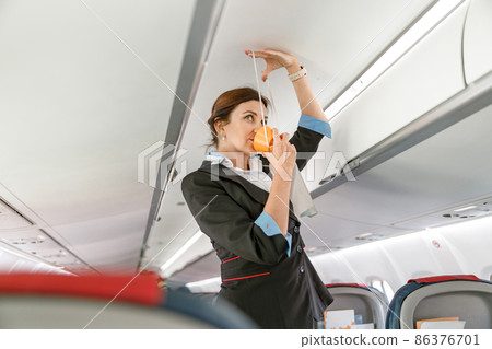 Flight attendant demonstrating how to use oxygen mask in airplane Flight attendant demonstrating how to use oxygen mask in airplane 86376701
