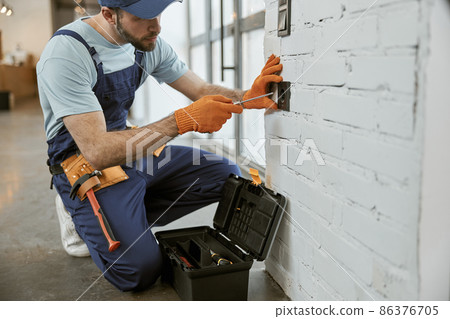 Male electrician fixing electrical wall socket with screwdriver Male electrician fixing electrical wall socket with screwdriver 86376705