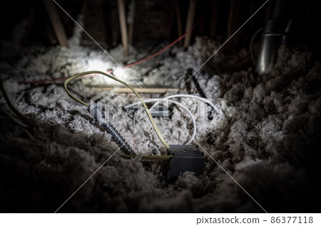 Electrical wire and conduit laying loose on blown insulation in a house attic. Electrical wire and conduit laying loose on blown insulation in a house attic. 86377118