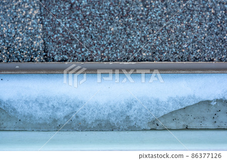 Ice and snow building up inside a rooftop gutter system on a residential house Ice and snow building up inside a rooftop gutter system on a residential house 86377126