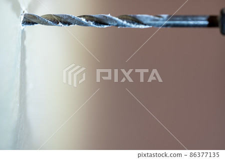 Selective focus on point of penetration of a drill bit making a pilot hole in drywall Selective focus on point of penetration of a drill bit making a pilot hole in drywall 86377135