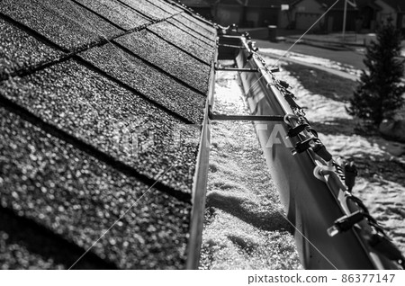 Ice and snow building up inside a rooftop gutter system on a residential house 86377147