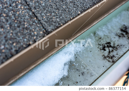 Ice and snow building up inside a rooftop gutter system on a residential house Ice and snow building up inside a rooftop gutter system on a residential house 86377154
