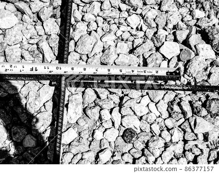 Inspecting and documenting the rebar overlap with a measuring tape at a construction job site 86377157