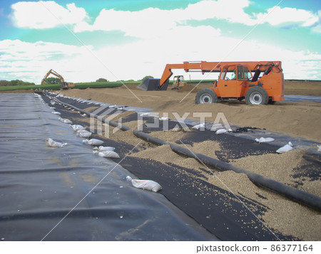 Installation of a leachate collection system under a new landfill with a liner and perforated rock. 86377164