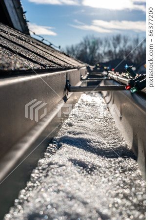 Ice and snow building up inside a rooftop gutter system on a residential house Ice and snow building up inside a rooftop gutter system on a residential house 86377200