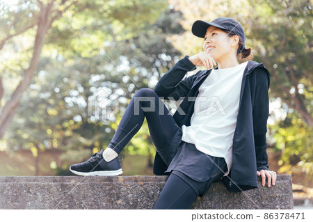 Female in sportswear resting in the park Female in sportswear resting in the park 86378471