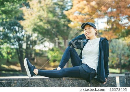 Female in sportswear resting in the park Female in sportswear resting in the park 86378495