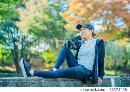Female in sportswear resting in the park Female in sportswear resting in the park 86378496
