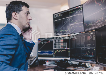 Stock broker trading online, talking on mobile phone. 86378792