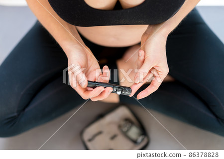 Pregnant Woman checking blood sugar level by glucometer and test stripe at home. Blood sugar testing at home. Female diabetic checking blood sugar levels. Pregnant Woman checking blood sugar level by glucometer and test stripe at home. Blood sugar testing at home. Female diabetic checking blood sugar levels. 86378828