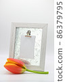 Wooden frame with note attached and a tulip flower. 86379795