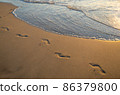 Footsteps on the golden sand with wave coming. 86379800