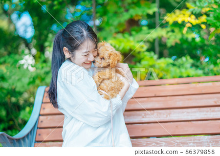Female playing with a dog in the park (embracing) 86379858