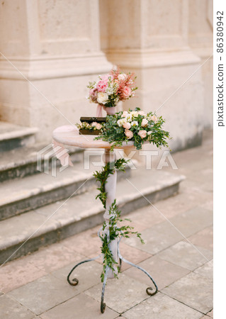 Reception, decorated with flowers and greenery, stands on the stone steps of the church 86380942