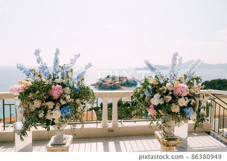 Lush bouquets of flowers in vases stand on the observation deck overlooking Sveti Stefan island Lush bouquets of flowers in vases stand on the observation deck overlooking Sveti Stefan island 86380949